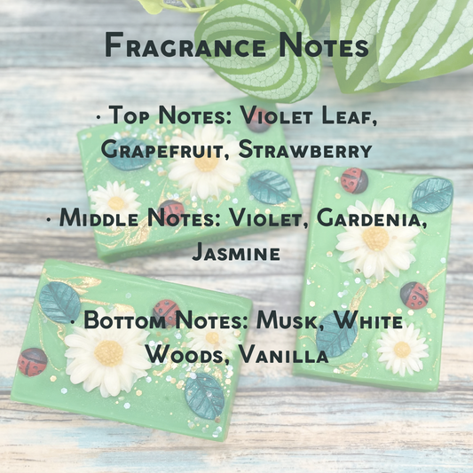 Three green soap bars with floral designs on a wooden surface, labeled with fragrance notes. Top: Violet Leaf, Grapefruit, Strawberry
Middle: Violet, Gardenia, Jasmine
Bottom: Musk, White Woods, Vanilla