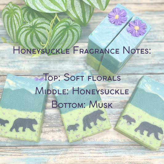 Four soap bars with honeycomb design and bear illustrations on a wooden surface, with text about honeysuckle fragrance notes.