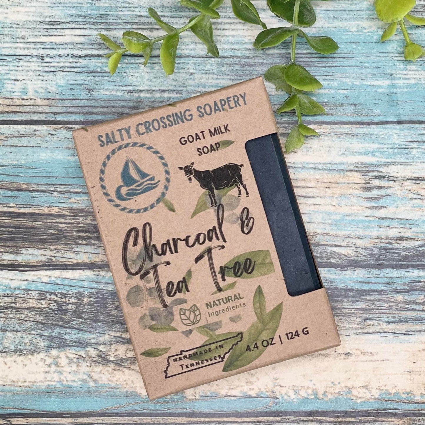 Bar of charcoal and tea tree goat milk soap in a printed Kraft box