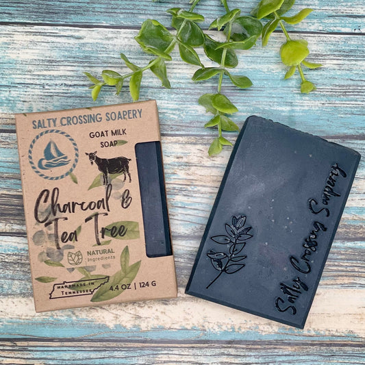 Charcoal and tea tree goat milk soap with box solid black soap bar with a stamp of plant line art and text salty crossing Soapery