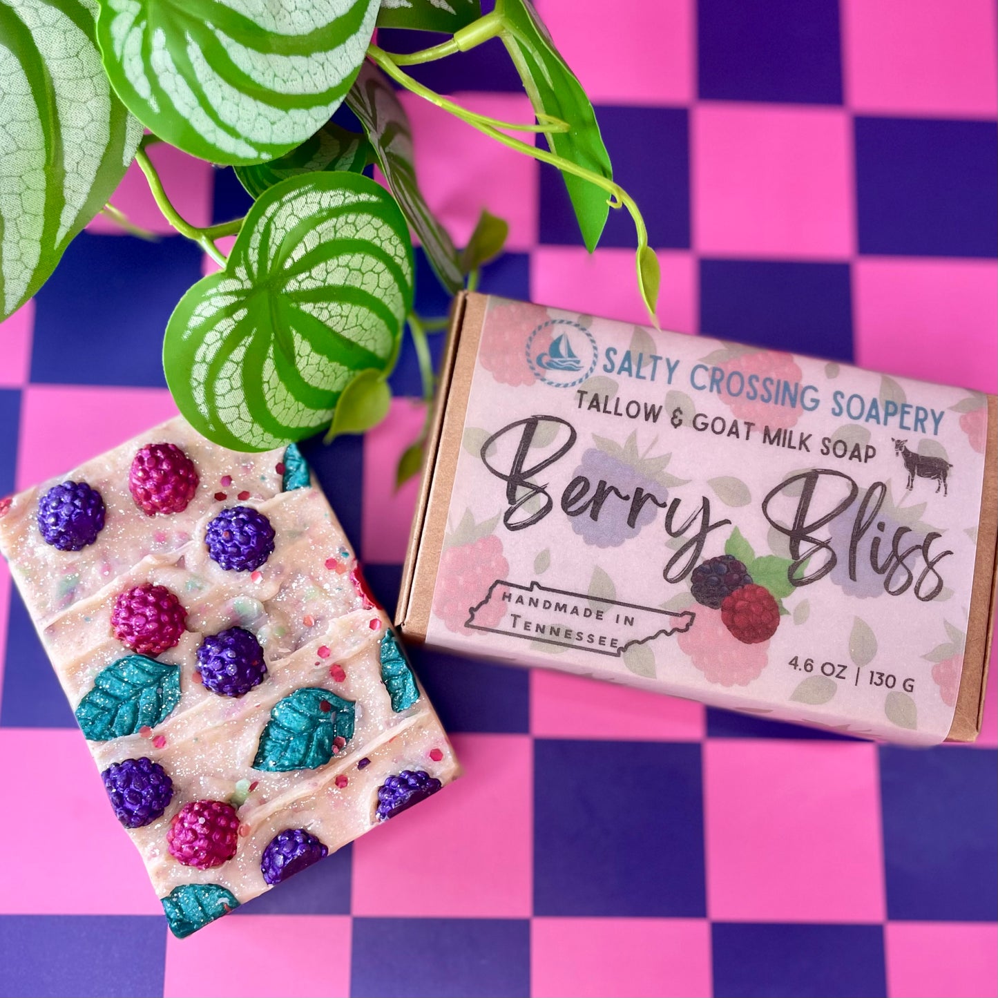Bar of soap with berry design and 'Berry Bliss' packaging on a checkered background