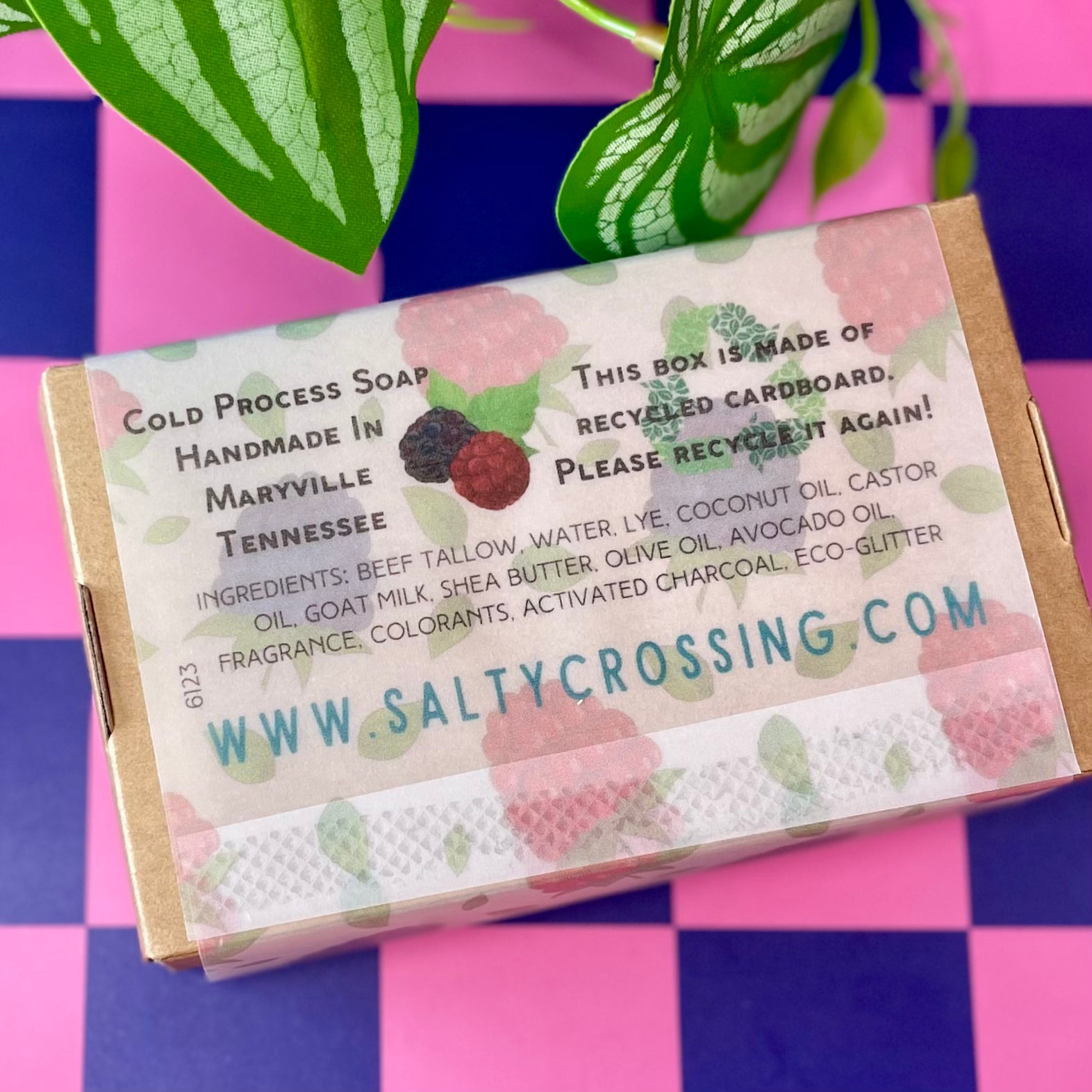 Soap packaging with a berry pattern label on a pink and blue checkered background