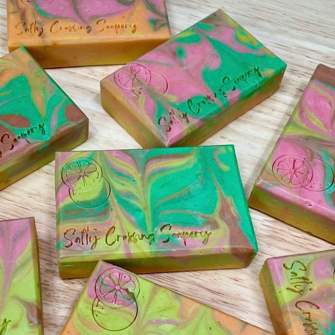 Colorful soap bars with marbled patterns and 'Salty Crossing Company' branding on a wooden surface.