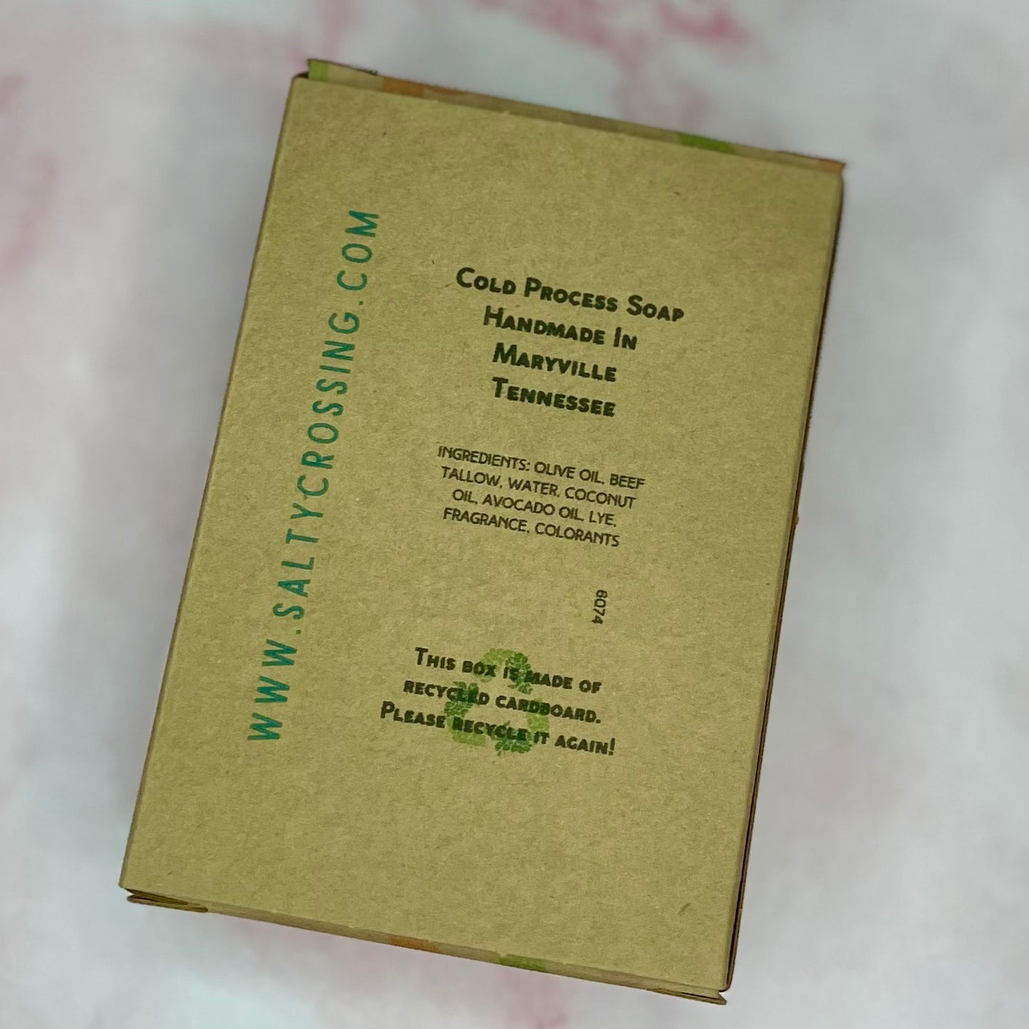 Brown cardboard soap packaging with text on a light pink background