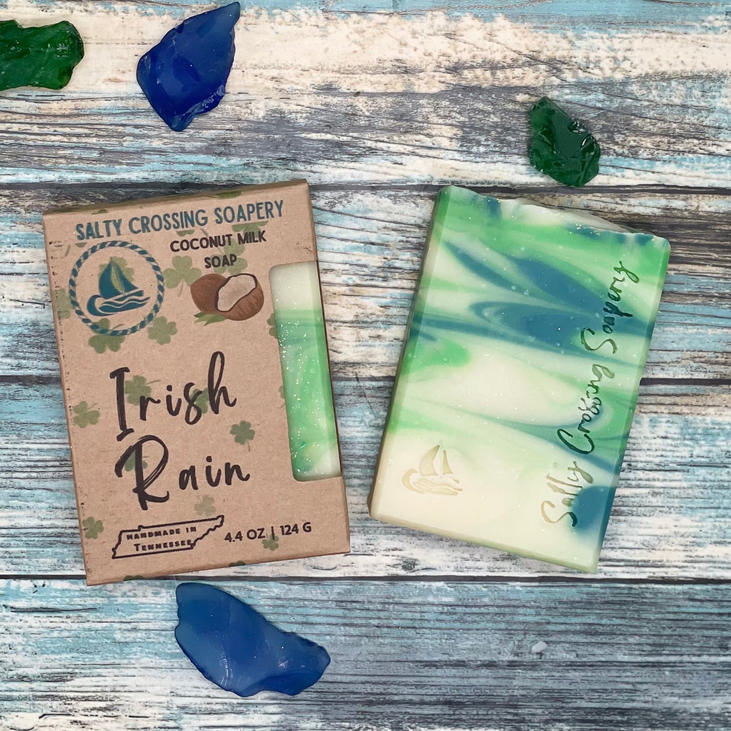 Irish rain handmade soap with box. Soap bar is green and white swirled with small sailboat graphic and salty crossing Soapery text stamped on the front. The box is kraft paperboard with color text and graphics