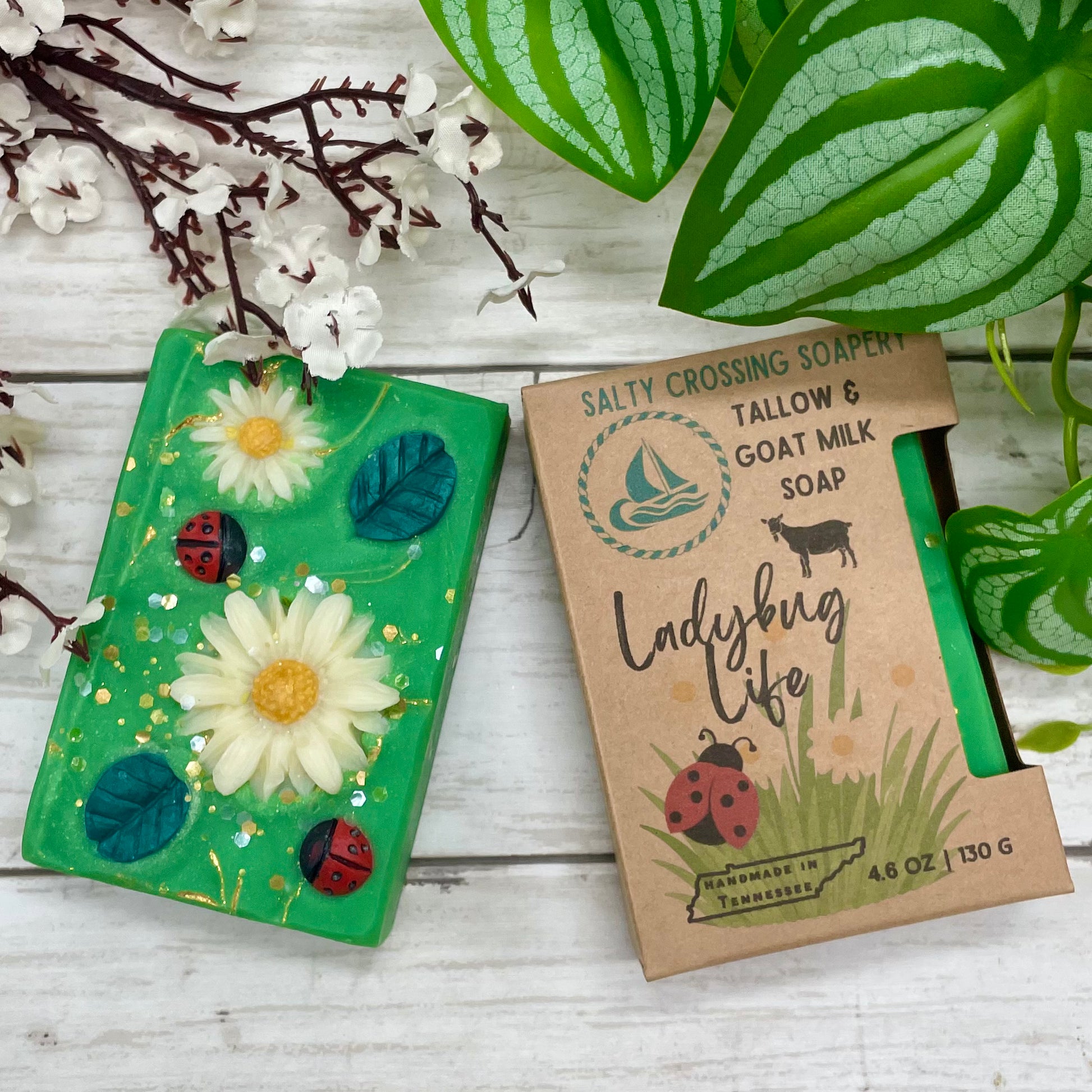 Soap with decorative elements on a wooden surface with plants and flowers.