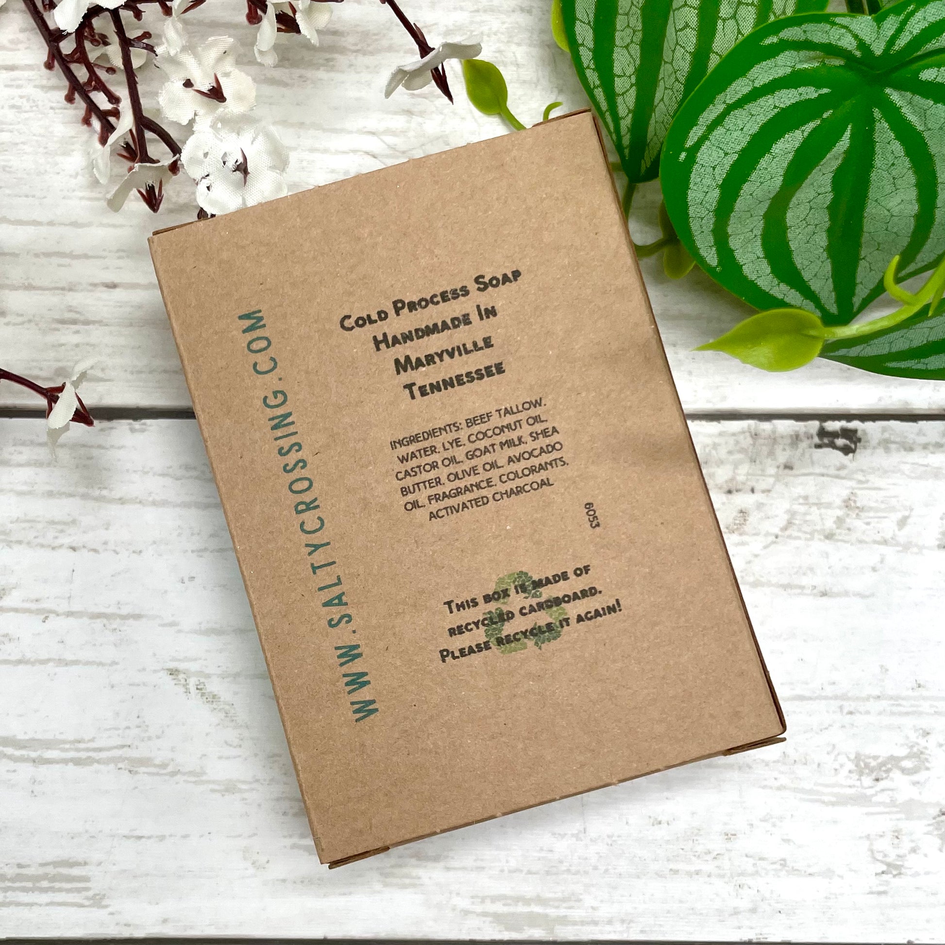 Kraft paper soap label with text on a wooden surface with plants