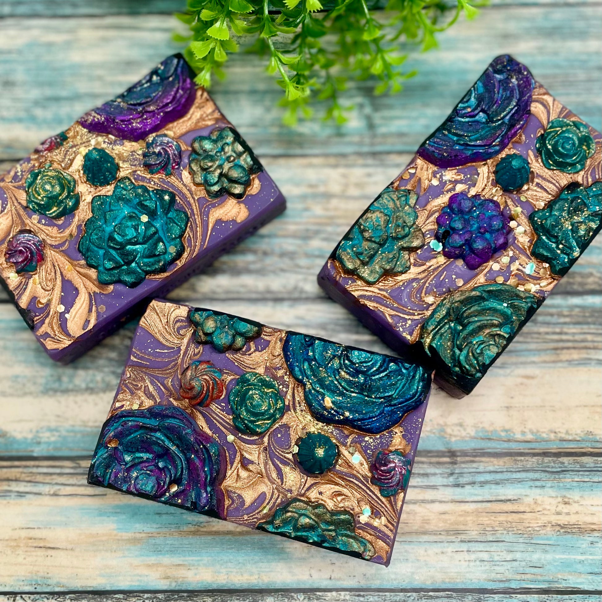 3 decorative purple soap bars topped with hand molded succulent shaped soap decorations. 