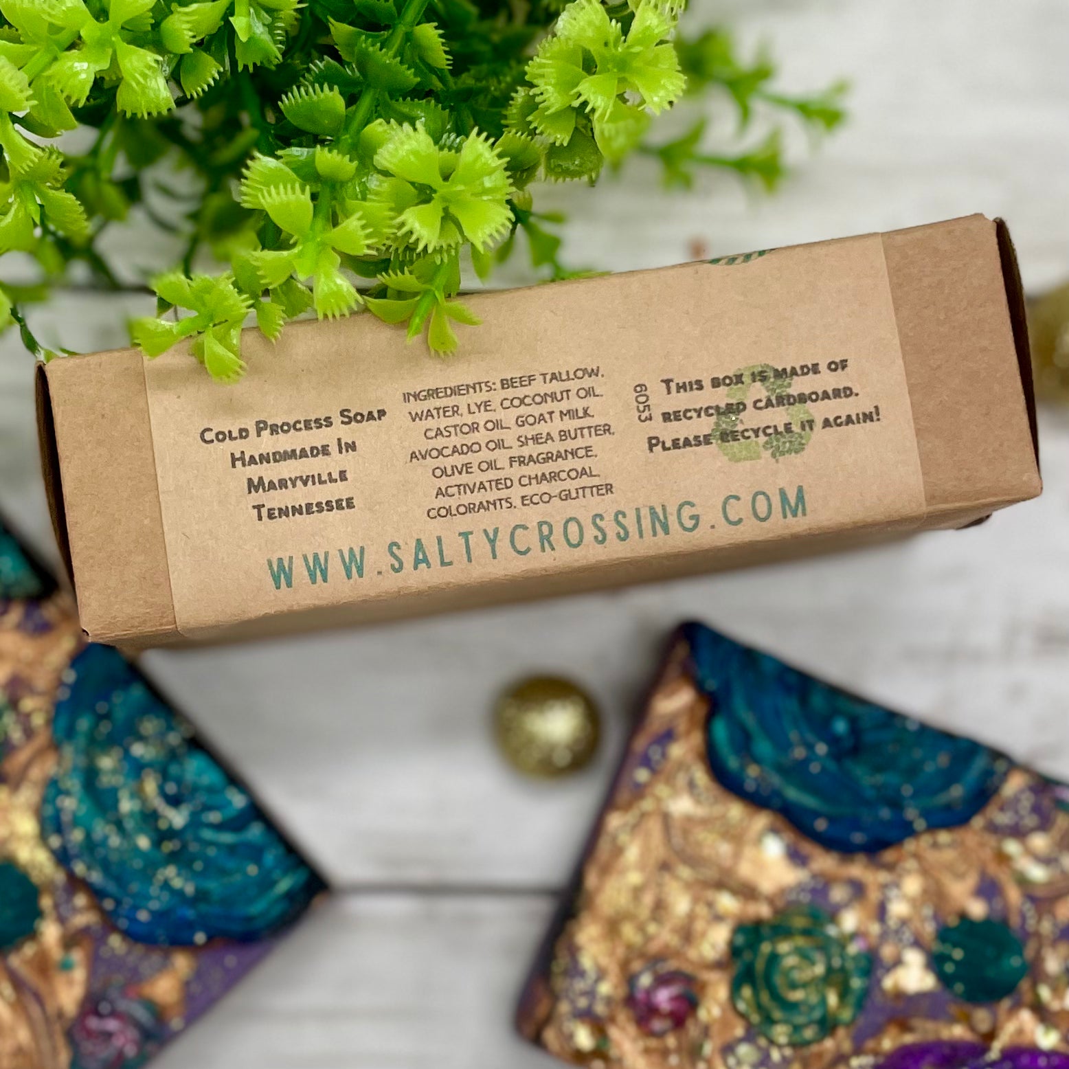 Cold process soap packaging with branding and recycling information on a decorative surface.
