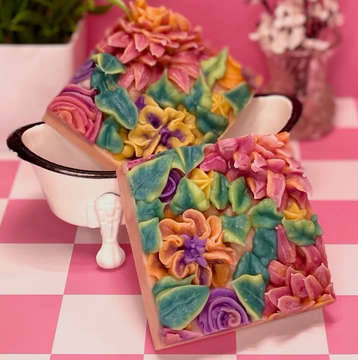Colorful floral-patterned soaps on a checkered tablecloth with plants in the background