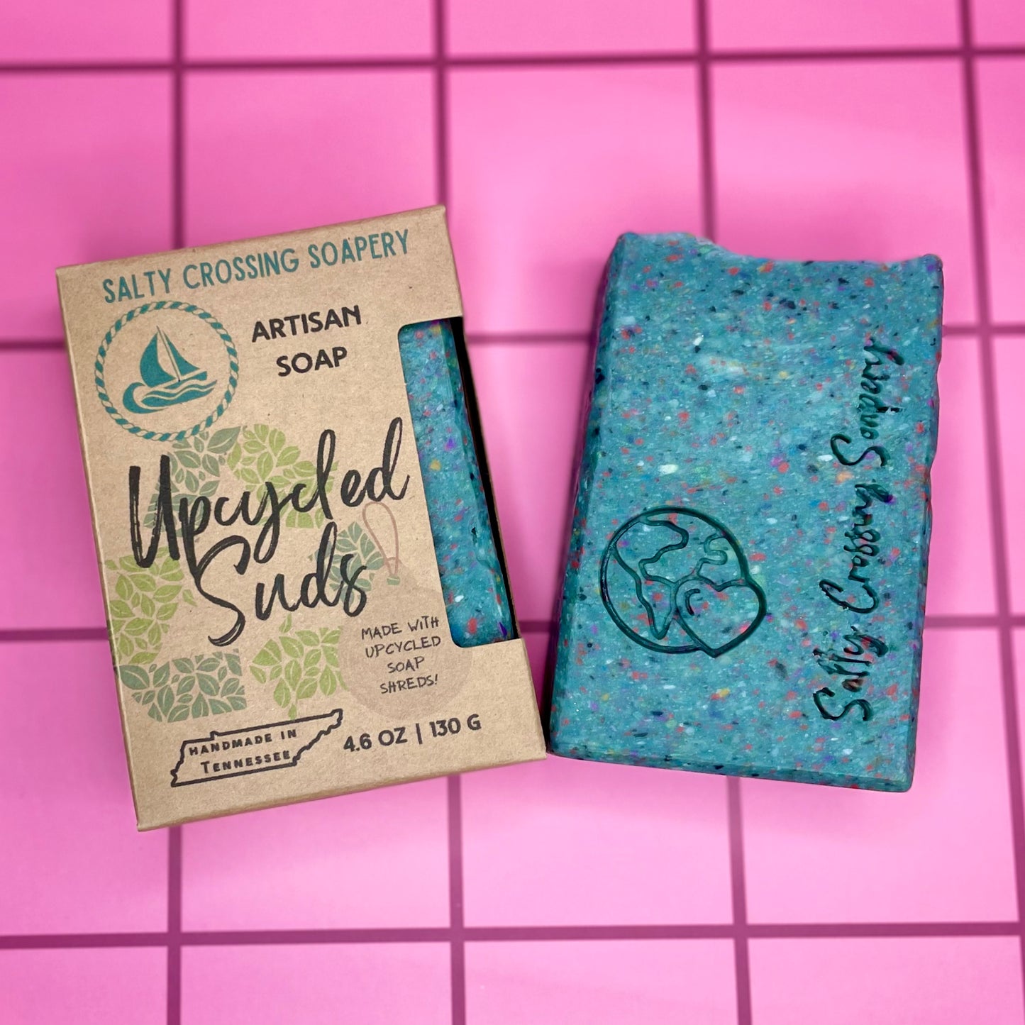 Artisan soap bar with packaging on a pink grid background