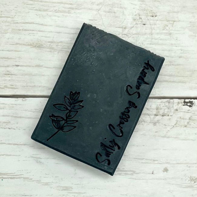 charcoal and tea tree natural goat milk soap bar. solid black, stamped with Salty Crossing Soapery