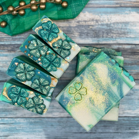 Feeling lucky handmade soap. White, green, and deep green swirls with a 4 leaf clover on the front of the bar. Topped with 2 shamrock embellishments and gold bio glitter 