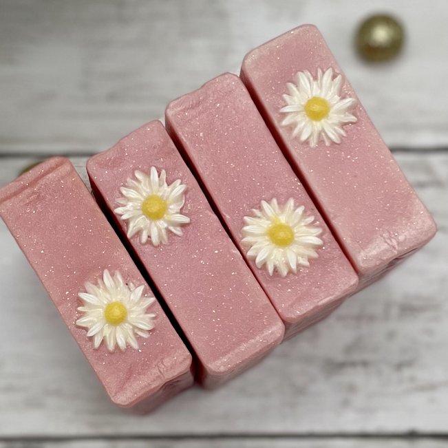 pink soap with white daisies on top close up