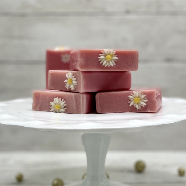 pink daisy soaps stacked on a white cake stand
