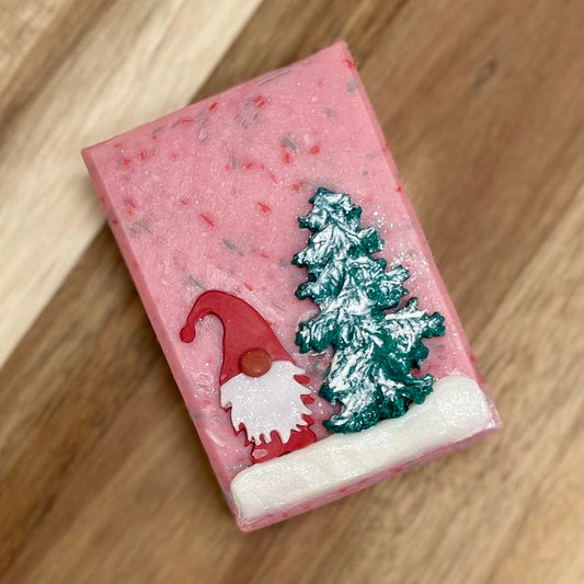 pink soap with red and green flecks. red gnome standing in snow with tree on the front.
