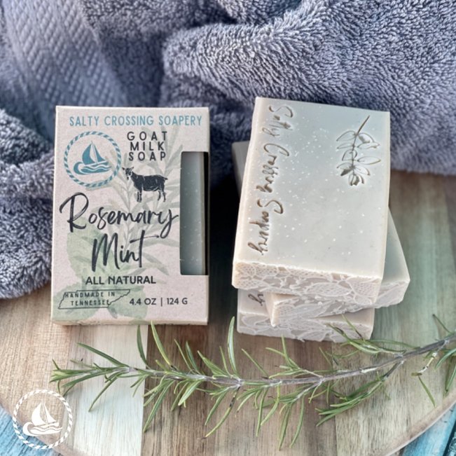 Rosemary mint goat milk soap with box. Pale tan-green bar stamped with plant graphic and salty crossing Soapery text