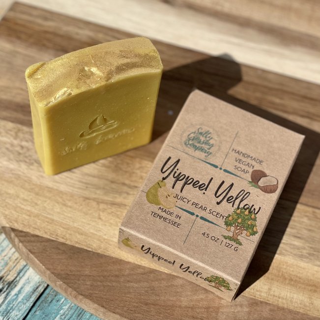 yippee yellow coconut milk artisan soap with box. yellow soap with gold sparkles on top. front of soap is stamped with salty crossing and sailboat. kraft colored box printed with pear and tree. handmade in tennessee.