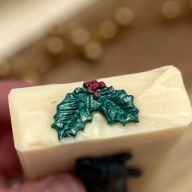 cream colored soap with holly leaves and berries on top