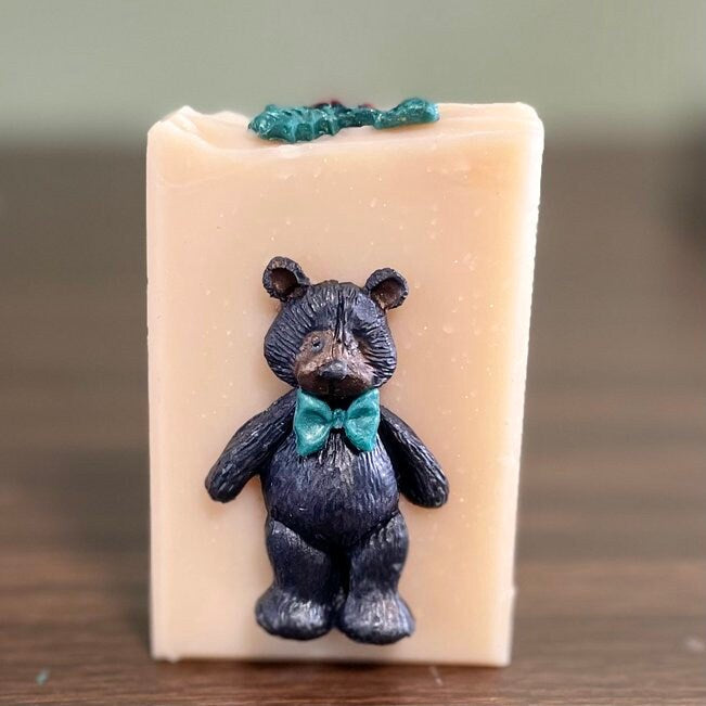 close up bear with green bow tie on cream colored soap.