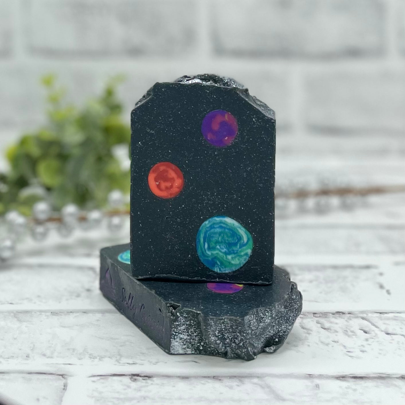Black soap with silver sparkles throughout and embedded planet design 